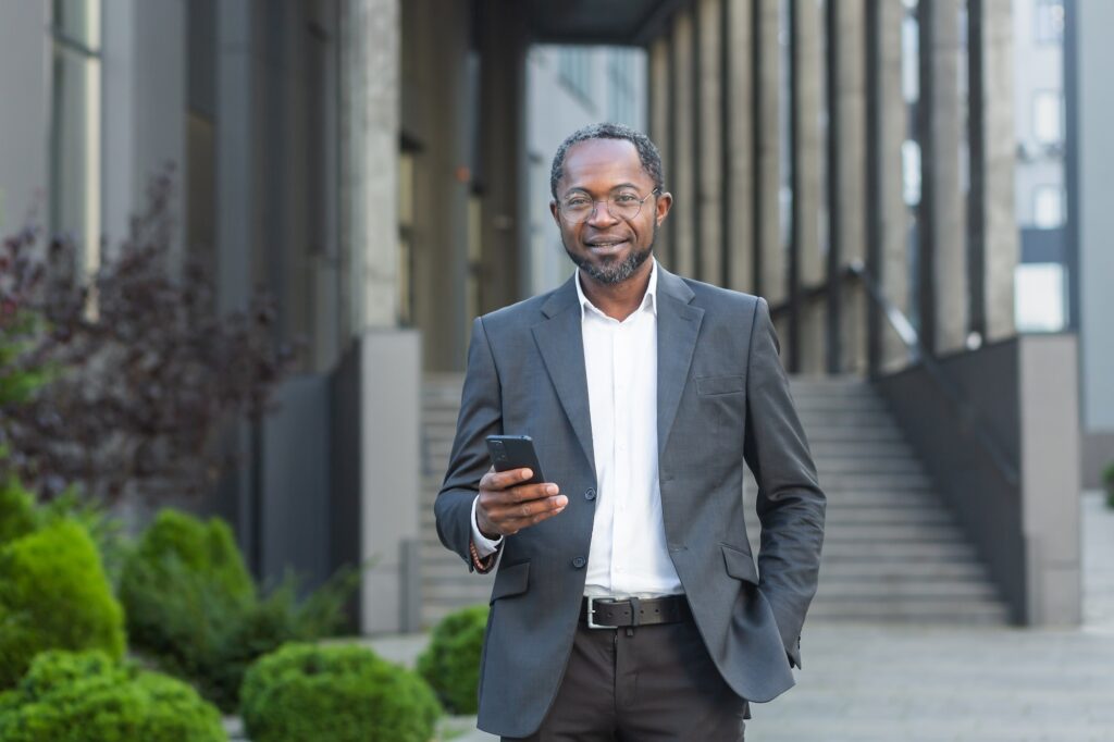 An African American male attorney. Who is standing near the courthouse, holding a phone in his hand