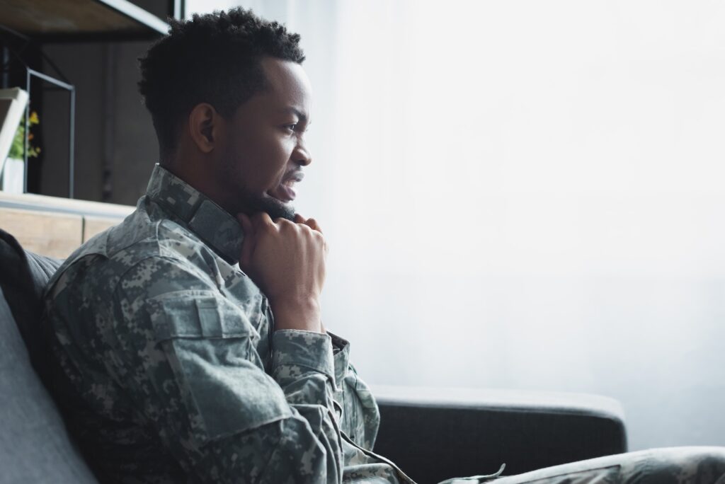 emotional african american soldier in military uniform suffering from PTSD at home