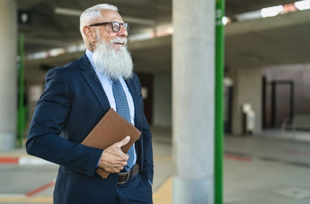 Happy senior business man holding digital tablet waiting in city bus station